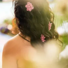 A detail shot of Yogita's Mehendi hairstyle. The soft curls adorned with delicate pink flowers perfectly matched the whimsical and romantic theme of her look.
