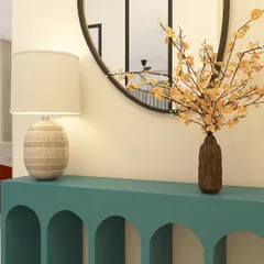 The entryway console sets the tone for the entire home. For this ATS Nobility foyer, we chose a striking teal console with arched details, paired with a simple round mirror and delicate floral arrangement to create a warm and stylish welcome.