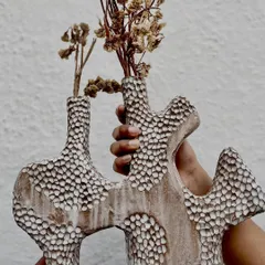 Holding up the finished, unglazed vase. The organic shape and detailed texture make this a true statement piece.