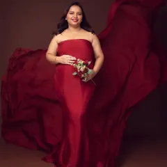 The power of red. This portrait features a gorgeous mom-to-be in a flowing red fabric drape, holding a bouquet that complements the rich color. The dark background makes the color pop.