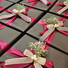This is a great example of how I balance corporate identity with a touch of glamour. For a collaboration between Shoppers Stop and Axis Bank, I used a sophisticated dark grey wrap with bold magenta and cream satin ribbons, finished with delicate baby's breath and pearls. It's a chic and elegant look perfect for high-end corporate gifting.