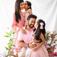 A candid moment of family love. This beautiful family portrait in shades of pink is full of sweet kisses and cuddles, capturing their natural connection in a light and airy setting.