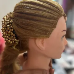 This practice style on a mannequin combines a textured ponytail with a sleek, wrapped base and a decorative bun accessory. It's a great example of the versatile party hairstyles we cover.