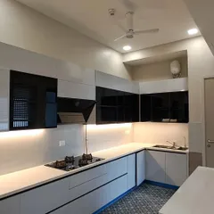 A recently completed kitchen at Paras Quartier, Gurgaon. This design showcases a modern black and white theme with sleek, glossy cabinets, under-cabinet lighting, and a patterned tile floor for a touch of character.