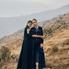 Two models styled in complementary denim looks for Ani Clothing. Their pose suggests a story of sisterhood and shared journeys against a vast, hilly landscape.