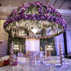 For a truly opulent wedding, I designed this magnificent mandap with a massive overhead dome of purple and pink flowers. The hanging chandeliers and lush green backdrop created a feeling of being in a magical, secret garden.