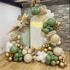 An elegant and earthy baby shower design. This setup uses a sophisticated palette of olive green, beige, and gold balloons, complemented by dried pampas grass and a custom neon sign for a modern, natural vibe.