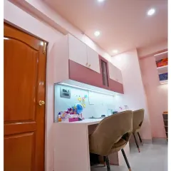 A practical and stylish study area for two. The design includes ample desk space, overhead cabinets for storage, and comfortable chairs, all in a soft, modern color palette.