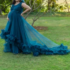This turquoise gown with a long, ruffled tail is perfect for an outdoor maternity shoot. The color stands out beautifully against natural greenery, and the lightweight fabric is easy to manage.