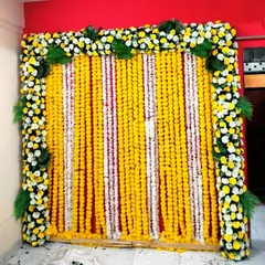 We created this dense floral backdrop using alternating strings of yellow and white marigolds. The entire curtain is framed with a border of white and yellow flowers and fresh palm leaves for a full, traditional look.
