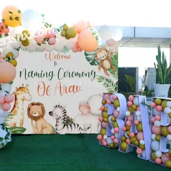 A charming naming ceremony decoration with a gentle jungle animal theme. The outdoor setup includes a personalized 'Welcome to Naming Ceremony' backdrop and 'BABY' marquee letters filled with balloons.