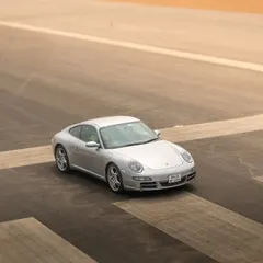 A minimalist shot focusing on the clean design of a Porsche 911, using the runway markings to create a strong compositional frame.