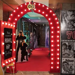 The entrance to the retro-themed 60th birthday, featuring a glowing arch and a personalized 'Now Celebrating' sign to make guests feel like stars.