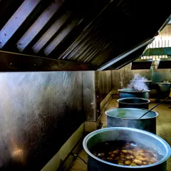 Large-scale preparation in our professional kitchen. Multiple large pots simmer away, each containing a different component of a traditional Baale Ele Oota, ready to serve hundreds of guests.