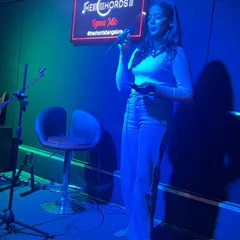 A singer confidently performs for the crowd at our Open Mic event. We provide the stage and support for artists to connect with an audience.