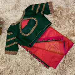 A classic festive combination of a bottle green hand-embroidered blouse with a bright pink silk saree, finished with a traditional black krosha tassel border.