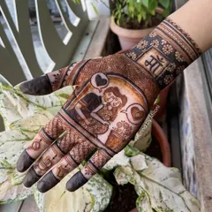 A close-up of a baby shower mehendi. This design features a loving portrait of the parents-to-be, with the word "Maa" (Mother) on the wrist.