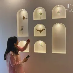 A candid moment of our client admiring the newly finished accent wall in her home. The illuminated niches with bird and flower decals have become her favorite corner.