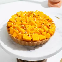 Our magical Mango Tart, with a crisp pastry shell filled with cream and piled high with fresh, sweet mangoes.