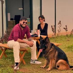 A perfect weekend scene: good company and a happy dog relaxing by the picnic table at our outdoor cafe.