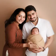 The sweetness of a new family. This classic studio portrait captures the proud smiles of the new parents as they hold their precious, sleeping baby.
