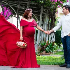 The flowing train of a maternity gown adds such a dramatic and elegant touch to outdoor photos. Here, the vibrant red contrasts beautifully with the garden setting, creating a truly show-stopping portrait.