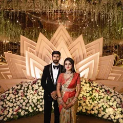 A full-length portrait of the couple standing before their magnificent floral and gold reception stage. This classic shot is a must-have for any wedding album.