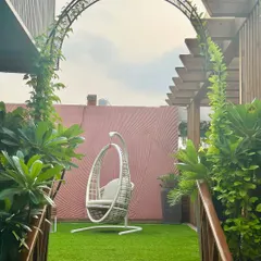 A perfect urban retreat designed by our team. This terrace features a lush artificial lawn, a climbing vine archway, and a comfortable swing chair, offering a peaceful garden view against the city skyline.