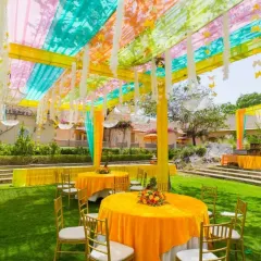 An outdoor garden setup for a Mehendi function in Noida. I used a light, multi-colored canopy with hanging tassels and bright yellow tablecloths to create a cheerful and sunny vibe.
