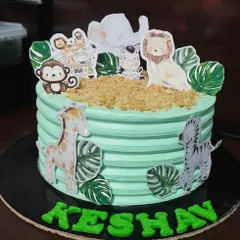 Here is another take on the popular jungle animal theme. This eggless cake features a light green frosting and is adorned with friendly safari animals like an elephant, zebra, and lion, perfect for a young explorer's birthday.