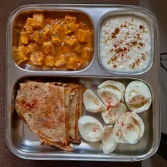 This plate features a high-protein combination of paneer curry with methi paratha, boiled egg whites, and a side of raita.