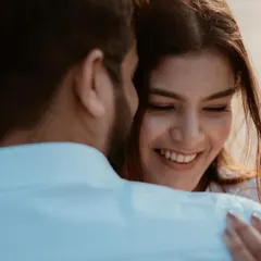 A beautiful over-the-shoulder shot focusing on the bride's joyful expression as she embraces her partner. This highlights pure, candid emotion.