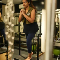 A client performs a single-leg squat on the Pilates chair, an exercise that builds balance, leg strength, and deep core stability. This functional movement translates directly to better performance in sports and daily life.