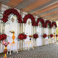 A statement stage for a grand engagement or wedding event. This backdrop features five golden arches adorned with lush red roses, creating a look of pure luxury.
