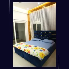 A luxurious bedroom design featuring a tufted blue velvet headboard and a striking accent wall with vertical white and black slats.