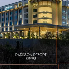 The contemporary facade of Radisson Resort, Khopoli, illuminated at dusk. The architecture balances clean lines with warm, inviting lighting, establishing its presence as a modern urban resort nestled in a natural landscape.