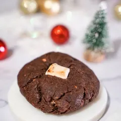 A rich, dark chocolate Christmas cookie with a marshmallow center. The minimalist setup focuses all attention on the delicious texture and ingredients of the cookie.