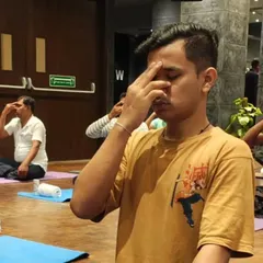 An employee practices Nadi Shodhana (Alternate Nostril Breathing) during a wellness workshop. This powerful pranayama technique is excellent for calming the nervous system, reducing anxiety, and improving focus in a high-pressure corporate environment.