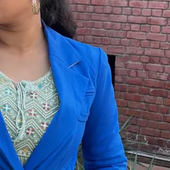 A detail shot of the outfit, focusing on the texture of the green dress under the sharp tailoring of the blue blazer. Small details make a big difference.