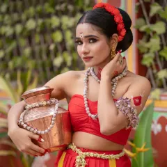 A beautiful portrait of a model in a traditional red outfit, holding a copper pot, embodying a classic Indian aesthetic.