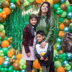 So much love in one frame! A mother and her children posing in front of the dinosaur-themed birthday decorations.