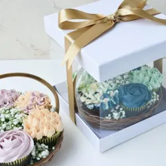 Here you can see how the cupcake basket is packaged for gifting. The clear-sided box protects the delicate buttercream flowers while showing off the beautiful arrangement, all tied with a gold ribbon.