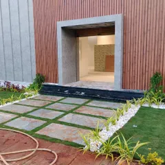 A modern entrance featuring a grid of stone pavers with grass growing between them. This technique, known as permeable paving, is both aesthetically pleasing and good for drainage.