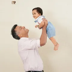 A sweet father-son moment, with dad lifting his baby boy into the air. This classic pose captures the joy and special connection they share.