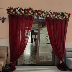 An elegant entrance for an engagement party, with deep red drapes and a thick floral border. This simple touch adds a lot of class to the venue's doorway.