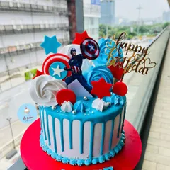 A heroic Captain America themed cake with a bold red, white, and blue design. This cake features a blue drip, buttercream swirls, and the iconic shield, perfect for a young superhero fan.