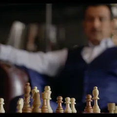 A blurry, artistic shot of Ronit Roy in the Sankalp Group ad. The focus on the chessboard in the foreground creates a sense of intellectual depth and power.