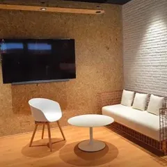 The reception area features a custom-designed wireframe sofa and a wall of raw pressed board. A large piece of monochrome art adds a powerful graphic element against the textured white brick wall.