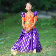 A full view of the custom Pattu Pavadai I made for the elder sister. The vibrant orange blouse with traditional puffed sleeves pairs beautifully with the royal purple silk skirt featuring a gold leaf pattern.