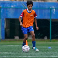 A young athlete focuses on close control while navigating a cone drill. These fundamental exercises are crucial for developing the agility and ball mastery needed in match situations.